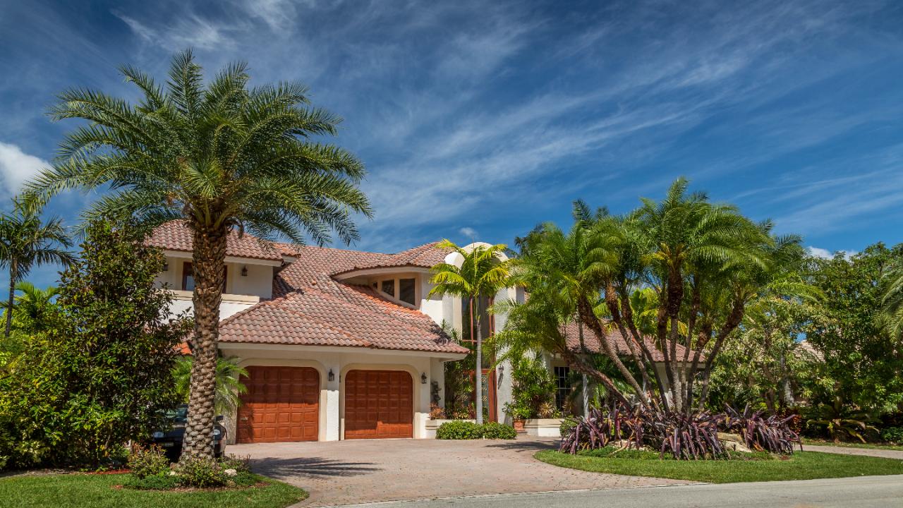 Tile roof Florida home with palms and a paver driveway